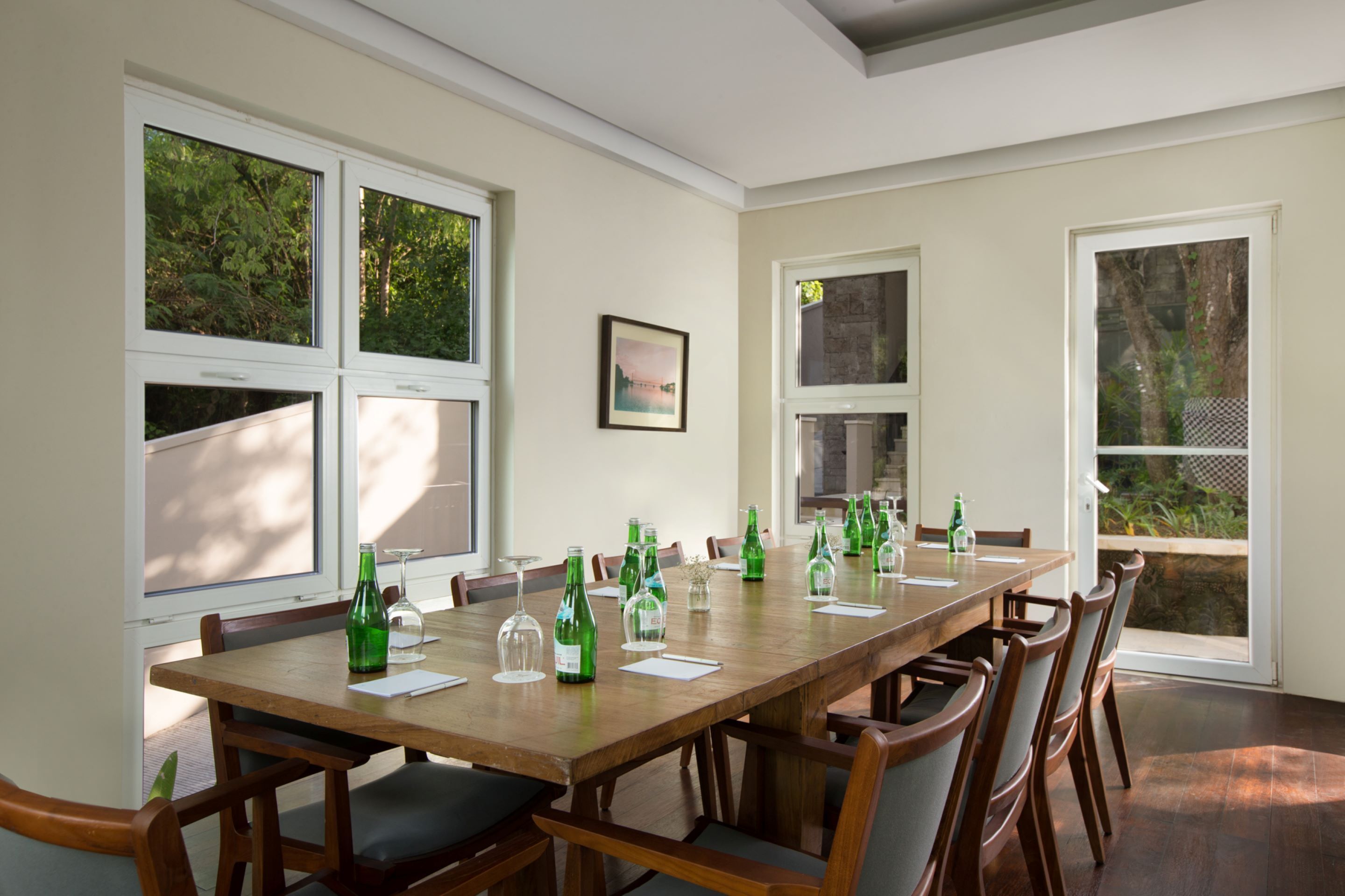 Comedor con una mesa de madera larga, varias sillas y ventanas amplias con vistas a zonas verdes.