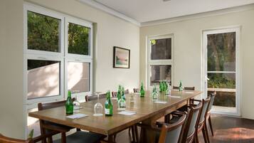 Comedor con una mesa de madera larga, varias sillas y ventanas amplias con vistas a zonas verdes.