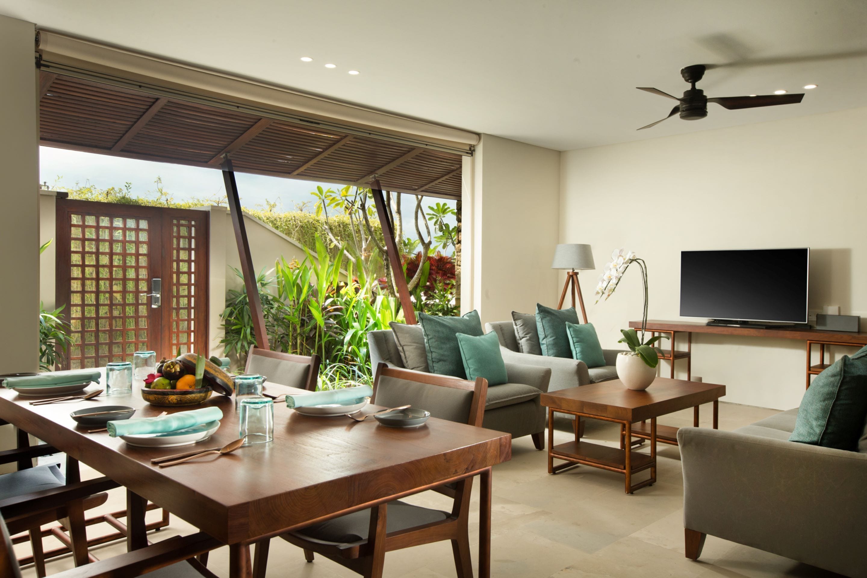 A modern living room with a dining area, a sofa set, a TV, and a ceiling fan.