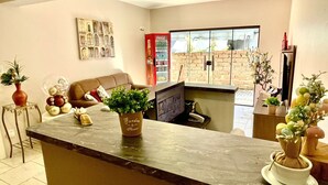 Una cocina con encimera de mármol, un refrigerador rojo Coca-Cola, pared de ladrillo y una ventana.
