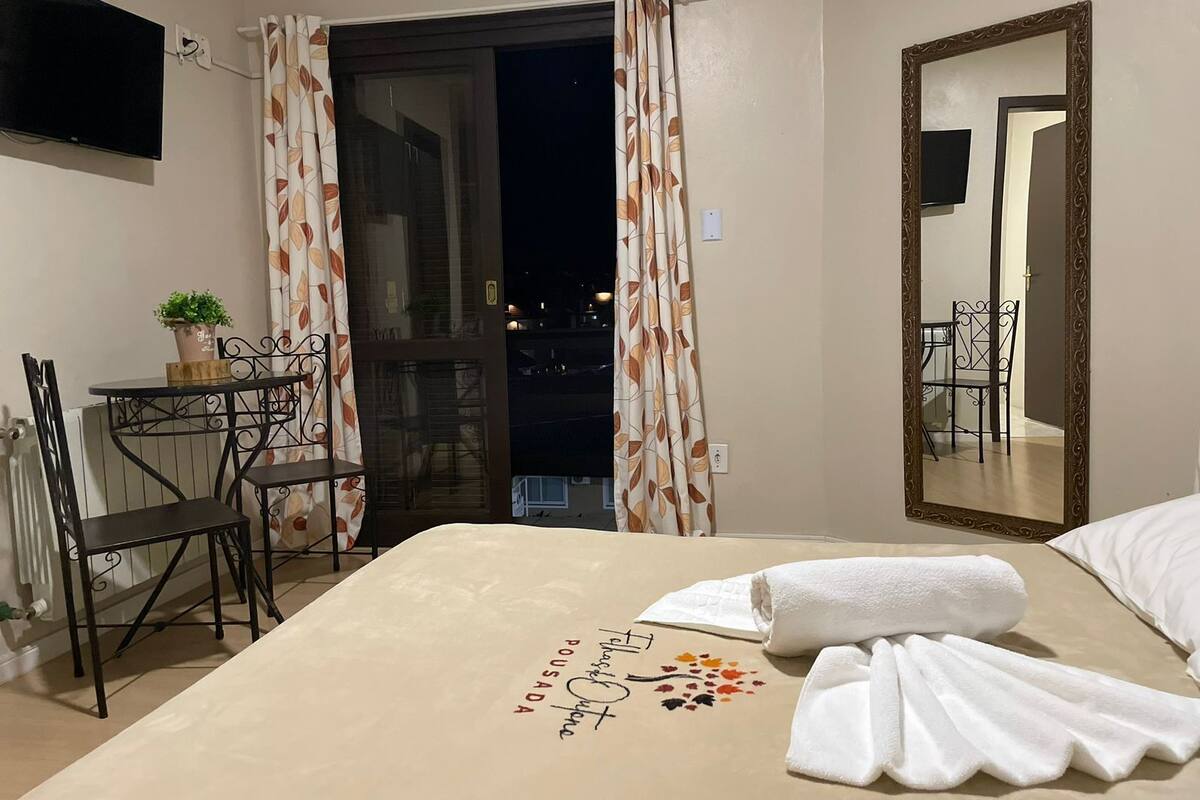 Ein Hotelzimmer mit Bett, Schreibtisch mit Stuhl, einer Zimmerpflanze und einer Balkontür.