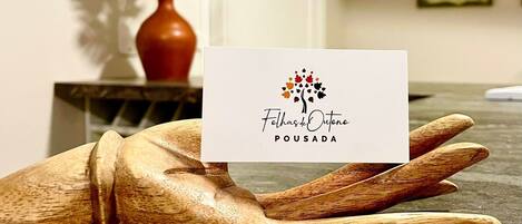 Uma mão segurando um cartão de visita com o texto 'Fethasdel Outono Pousada'.