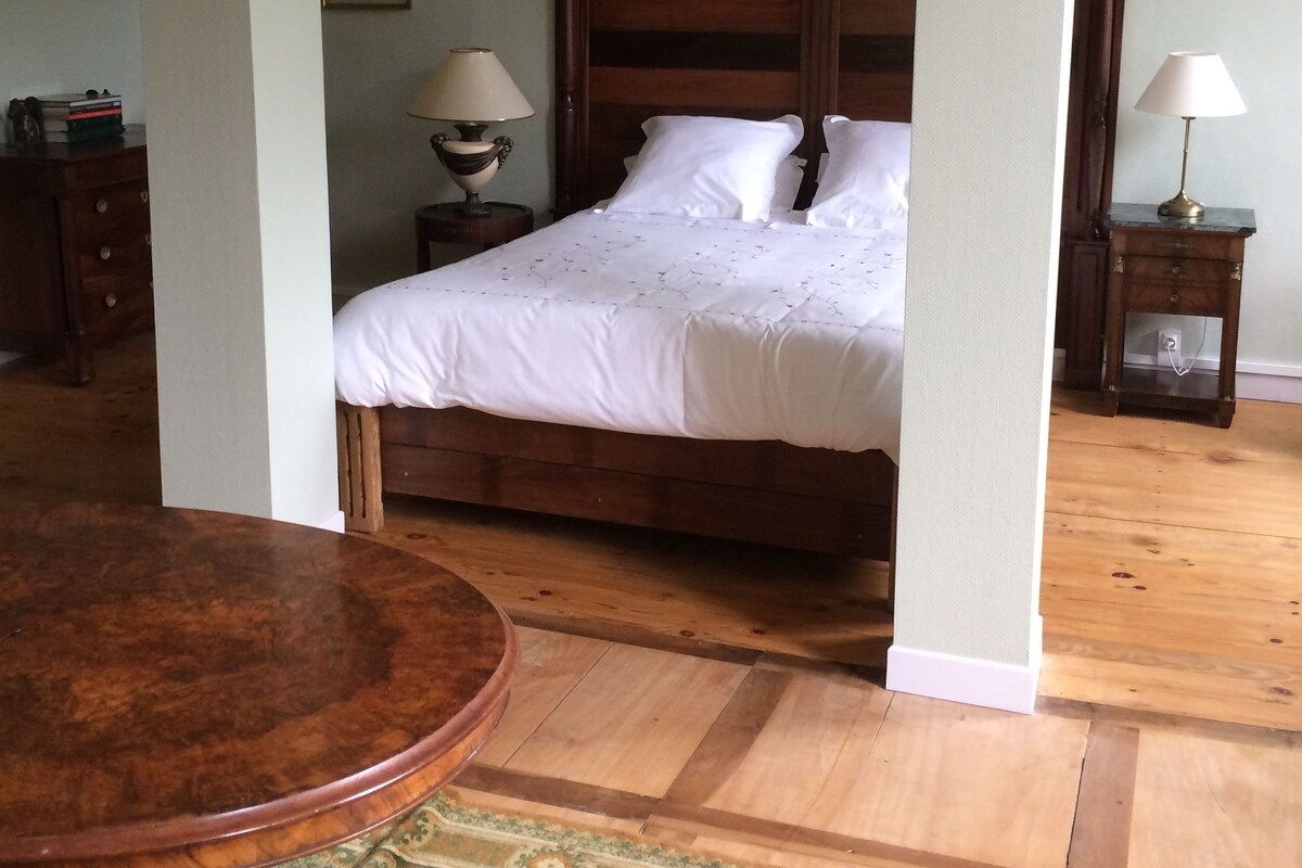 A bedroom with a wooden bed, a round table, and a patterned rug.