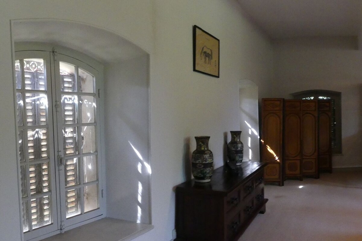 A traditional bedroom with a four-poster bed, a wooden dresser, and a desk with a chair.