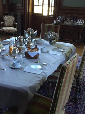A dining table set with silverware, plates, and glasses, with a basket of bread and a teapot on a white tablecloth. - Chateau du Val Larbont (La Bastide-de-Serou)