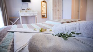 Une chambre à coucher avec un lit, une table de chevet, un miroir, une armoire et un téléviseur fixé au mur.