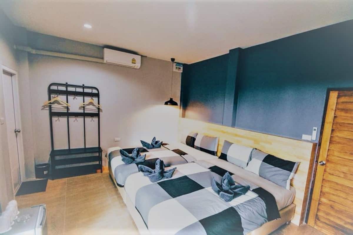 A bedroom with a bed, a wooden door, a coat rack, and a wall-mounted air conditioner.