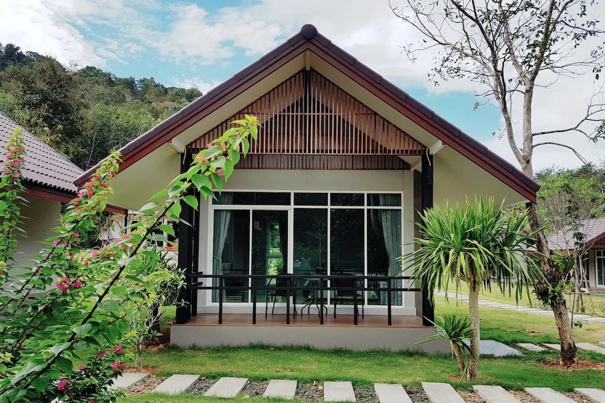 A modern house with a large front porch, a balcony, and a well-maintained garden.
