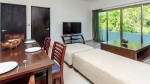 A modern room with a dining table set for two, a sofa, a TV, and a window with a view of greenery. - Davinci By Vtpvacaciones (Playa del Carmen)