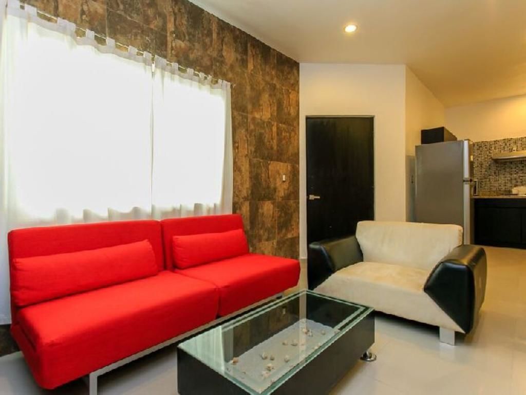 A living room with a red sofa, a white sofa, and a glass coffee table.