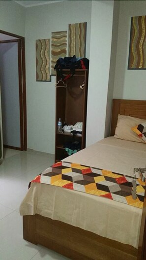 A bedroom with a bed, a wooden wardrobe, and a door.