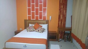 A hotel room with a bed, a wooden nightstand, a desk, and a chair. - Hospedaje Piolin (Tarapoto)
