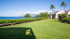 A well-maintained lawn with a clear view of the ocean and mountains in the background.
