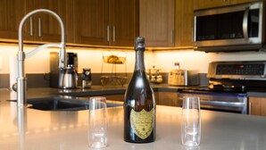 A kitchen counter with a bottle of champagne and two glasses.