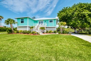 A turquoise two-story house with a white porch and a staircase leading to the front door.