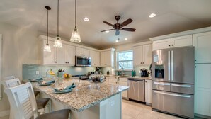 A modern kitchen with granite countertops, stainless steel appliances, and pendant lighting.