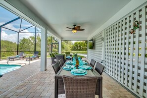 An outdoor patio with a pool, dining table, and chairs.