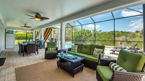 A spacious patio area with a green sofa, wicker chairs, and a dining table.