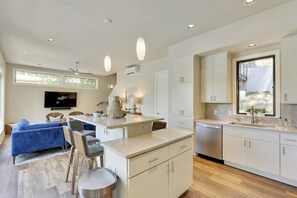 Een moderne keuken met een centraal eiland, witte kasten en een eethoek met blauwe meubels.