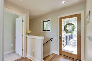 A hallway with a wooden door, a small window, and a wreath on the door.