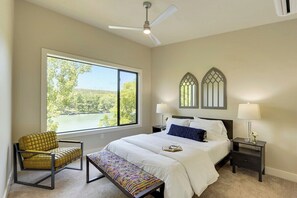 A bedroom with a large window, a bed with white linens, a bench, and a chair. - Minutes to Downtown Austin: Peaceful Waterfront Retreat with City Access Nearby (Austin)
