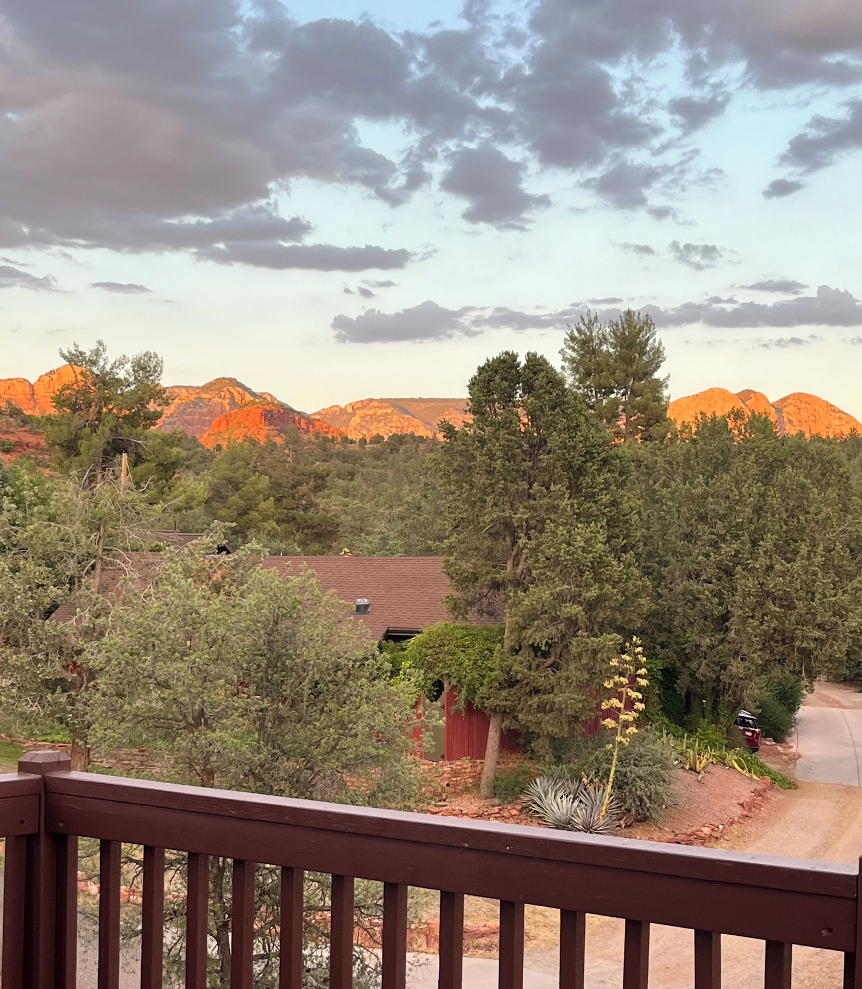 A view from a balcony overlooking a mountainous landscape with a red building in the foreground.