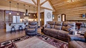 A spacious living area with a large sofa, a fireplace, and a wooden ceiling.