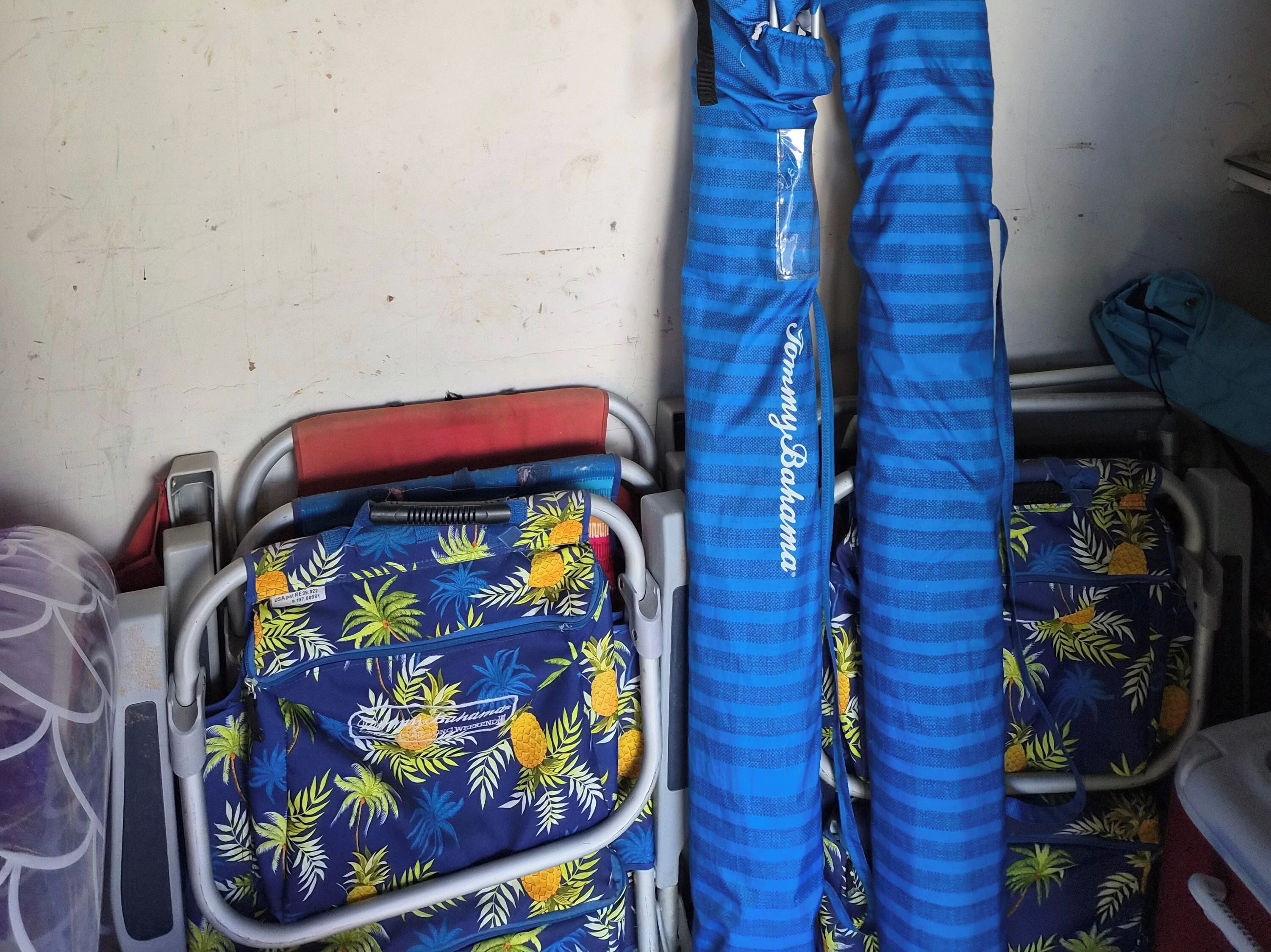 A luggage cart with a blue bag featuring a tropical leaf pattern and a blue striped bag with "Tommy Bahama" text.