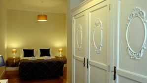 Ein Hotelzimmer mit einem Bett, zwei Nachttischlampen, einem Kleiderschrank mit verzierten Griffen und einer gemusterten Tapete.