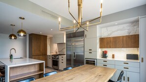 A modern kitchen with a central island, stainless steel appliances, and a wooden dining table.