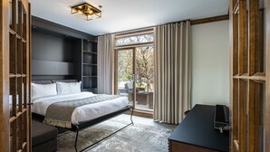 A modern hotel room with a bed, a desk, a wardrobe, and a large window with curtains.