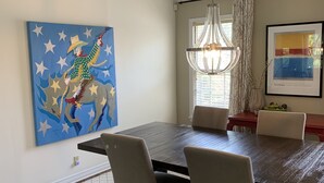A dining area with a dark wooden table, four chairs, a chandelier, and artwork on the walls.