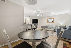 Een eethoek met een ronde tafel, stoelen en een plafondventilator.