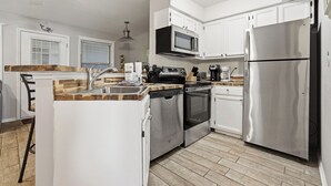 Eine Küche mit weißen Schränken, Edelstahlgeräten, einer Mikrowelle, einem Backofen und einem Kühlschrank.