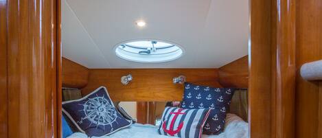 A bedroom with a bed, wooden headboard, and a ceiling light.