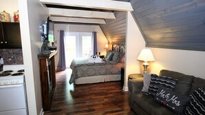 Ein gemütliches Schlafzimmer mit einem Bett, einem Nachttisch, einer Lampe und einem Sofa mit dekorativen Kissen.