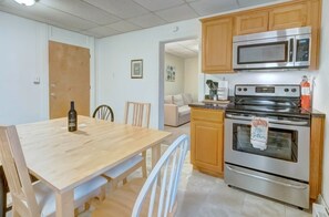 A kitchen with wooden cabinets, a stainless steel oven, a microwave, and a dining table with chairs. - Penn Stater, Apt #7 (Hershey)
