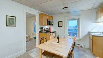 A compact kitchen with wooden cabinets, a microwave, and a dining table with chairs.