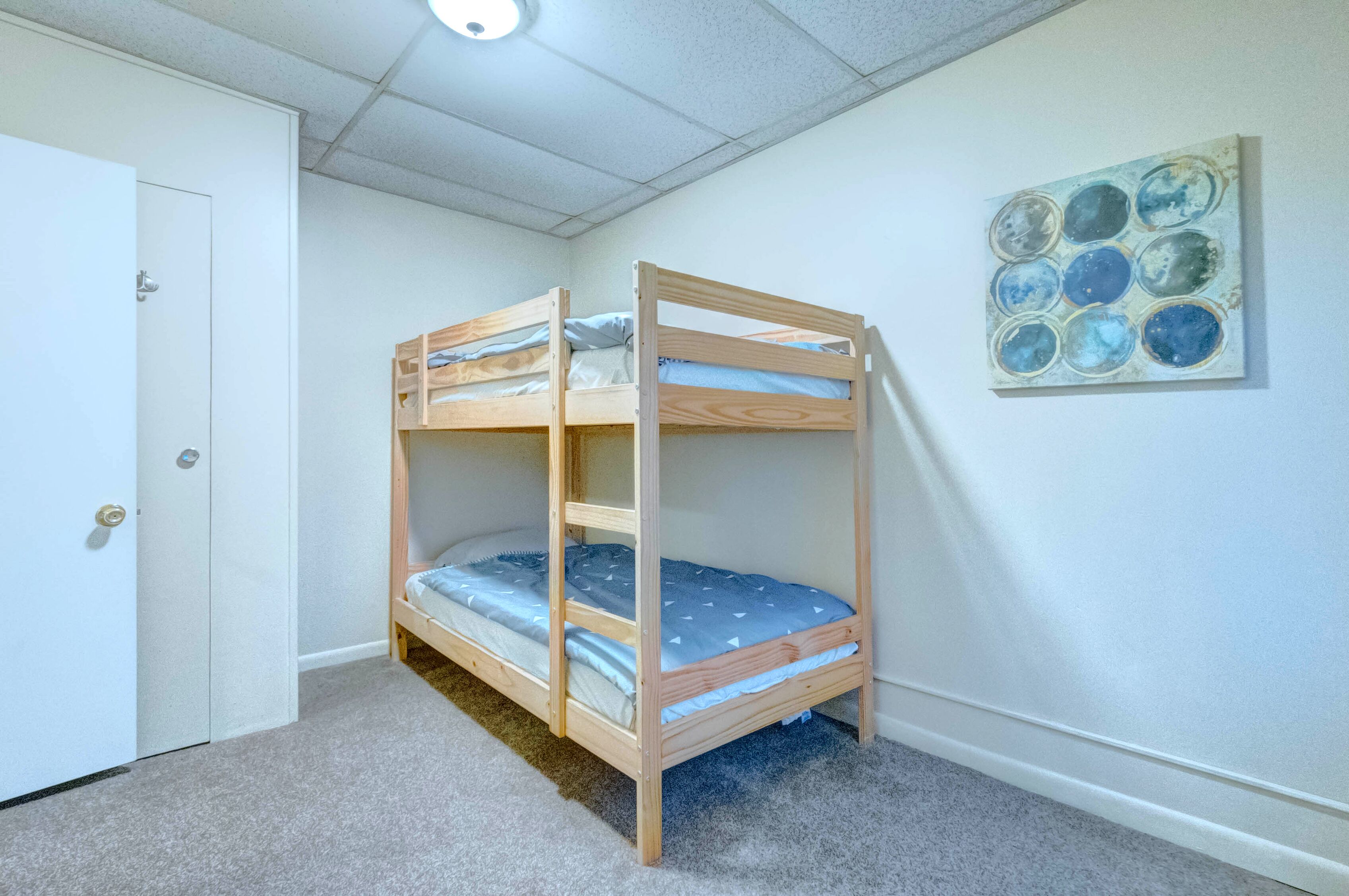 Una cama litera en una habitación con una puerta y una obra de arte en la pared.
