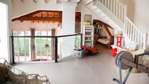 Un vaste espace de vie doté d’un haut plafond, d’un escalier et offrant une vue dégagée grâce à de grandes fenêtres.