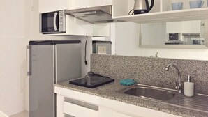 A modern kitchen with a built-in microwave, a stainless steel refrigerator, and a granite countertop.