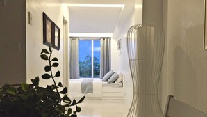 A modern interior with a seating area by a large window, a potted plant, and a unique light fixture.