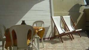 A covered outdoor seating area with white plastic chairs and a table, a satellite dish, and a concrete wall. - Apartment/ flat - ESSAOUIRA (Essaouira)