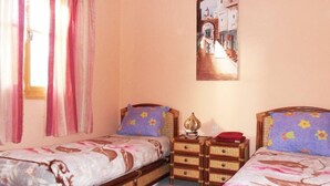 A bedroom with two single beds, a nightstand with a lamp, and a painting on the wall. - Apartment/ flat - ESSAOUIRA (Essaouira)