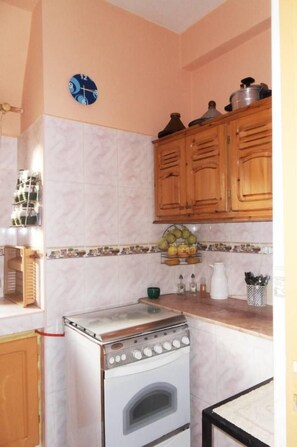 A kitchen with wooden cabinets, a stove, and a clock on the wall.