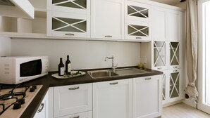 A modern kitchen with white cabinetry, a stainless steel sink, and a microwave.