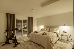 Hotelkamer met een bed, een hometrainer en uitzicht door een schuifdeur.