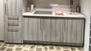 Una cocina moderna con armarios grises de madera, una encimera blanca y una estufa integrada.