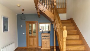 A wooden staircase with a handrail, a door with a mirror, a cabinet with a lamp, and a ceiling light fixture. - Stunning modern home in a perfect location (Ballycastle)