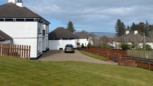 A residential area with a white house, a driveway, and a car parked in front. - Stunning modern home in a perfect location (Ballycastle)